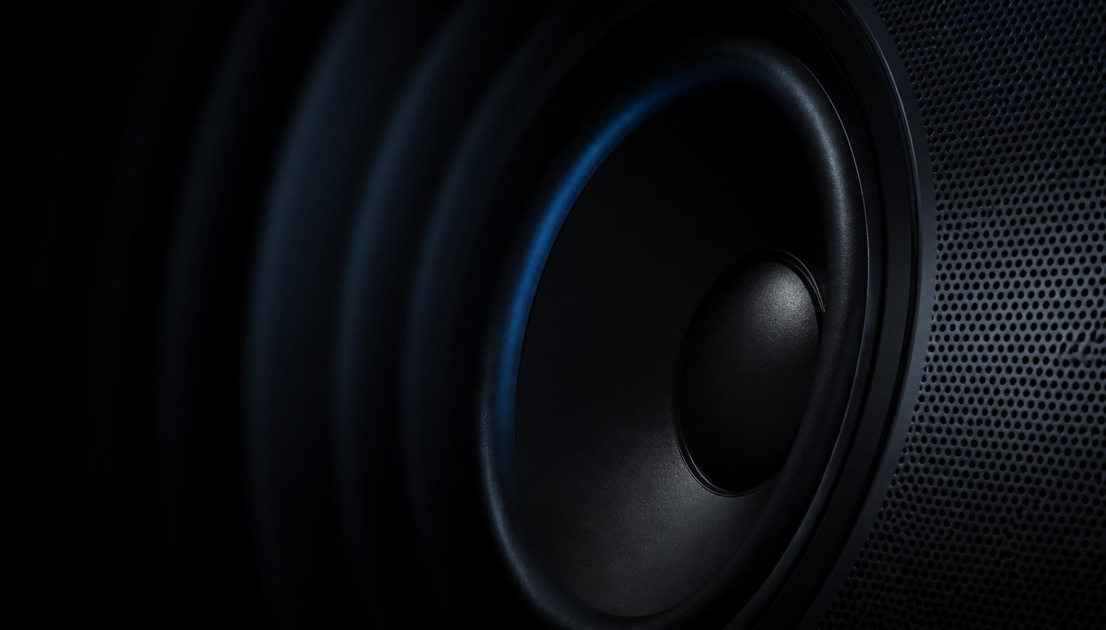 Close-up of a premium speaker driver and perforated grille lit with a faint blue edge